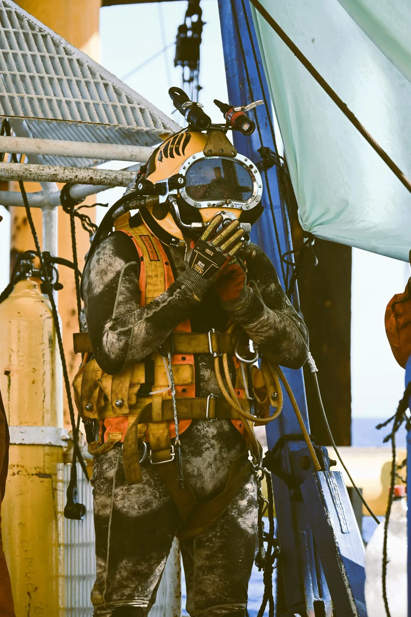 A commercial diver in a helmet on deck before a dive